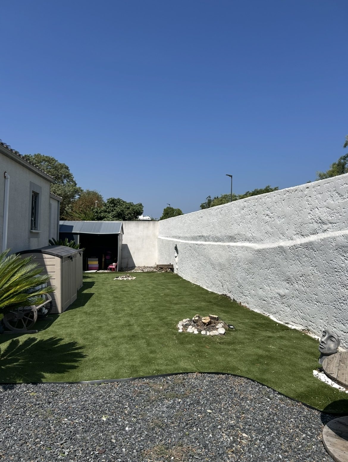 Jardin avec gazon synthétique et massif de galets